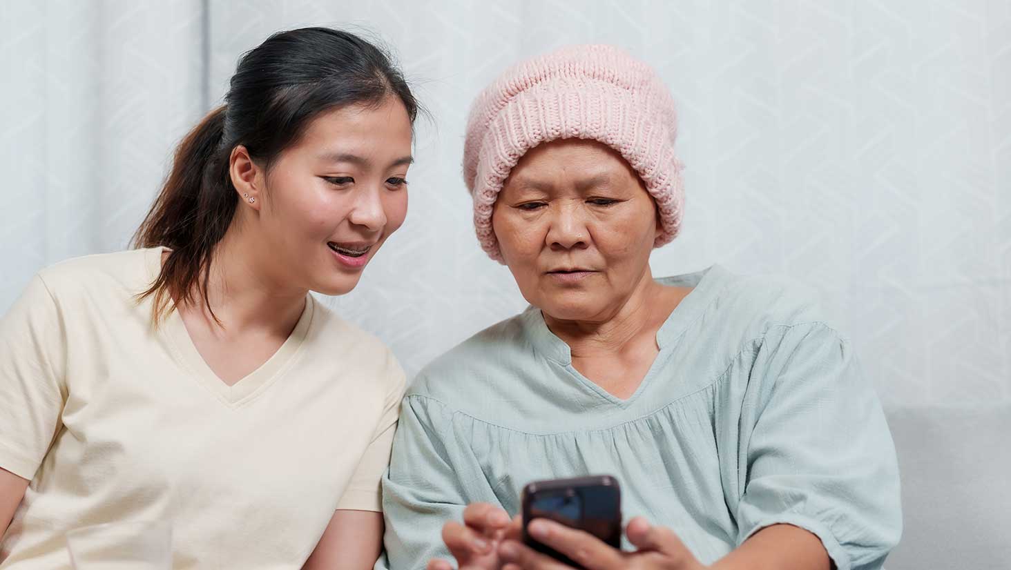 Grandmother sharing family caregiving solution app with granddaughter.