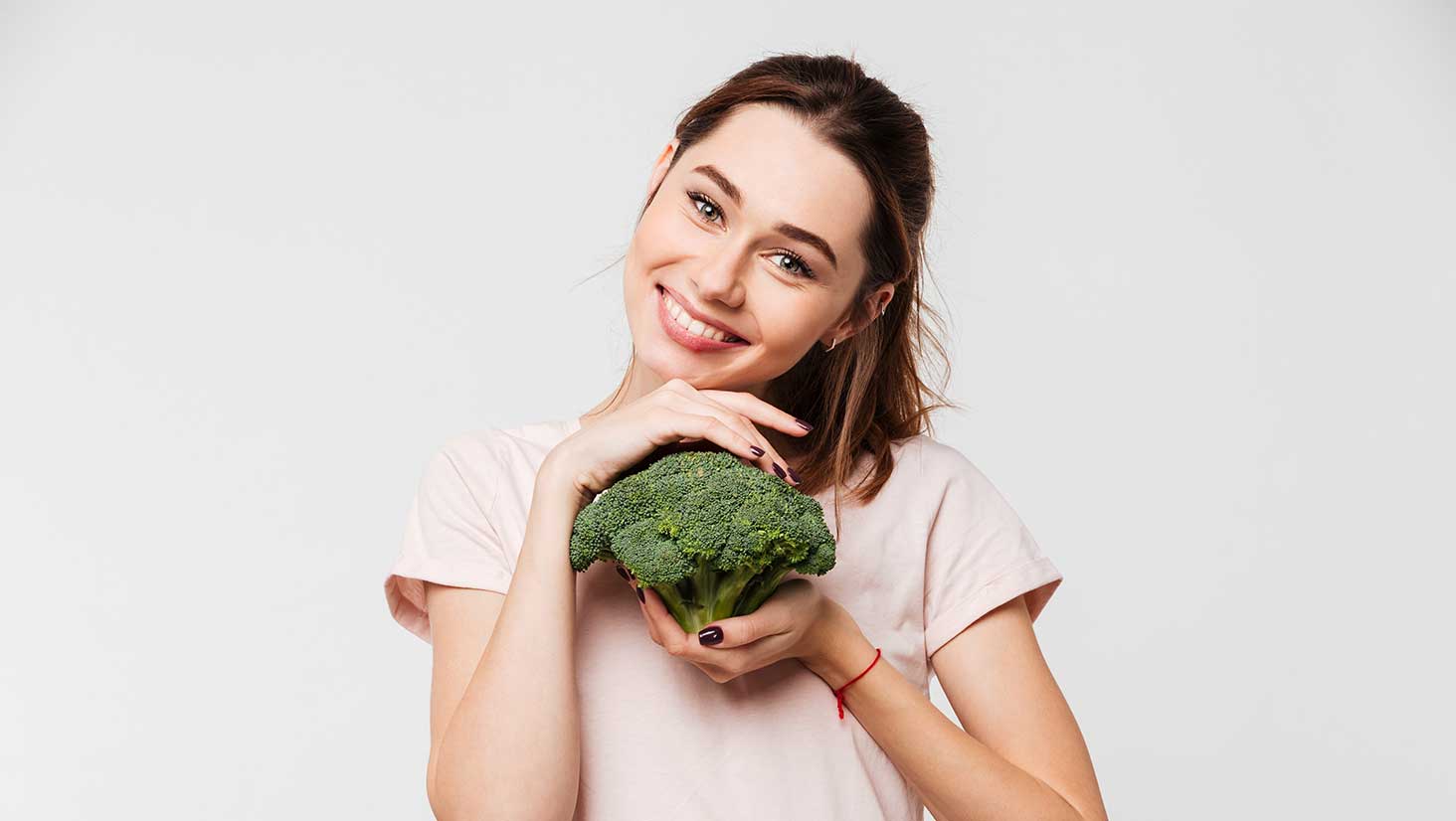 Photo of young woman holding broccoli