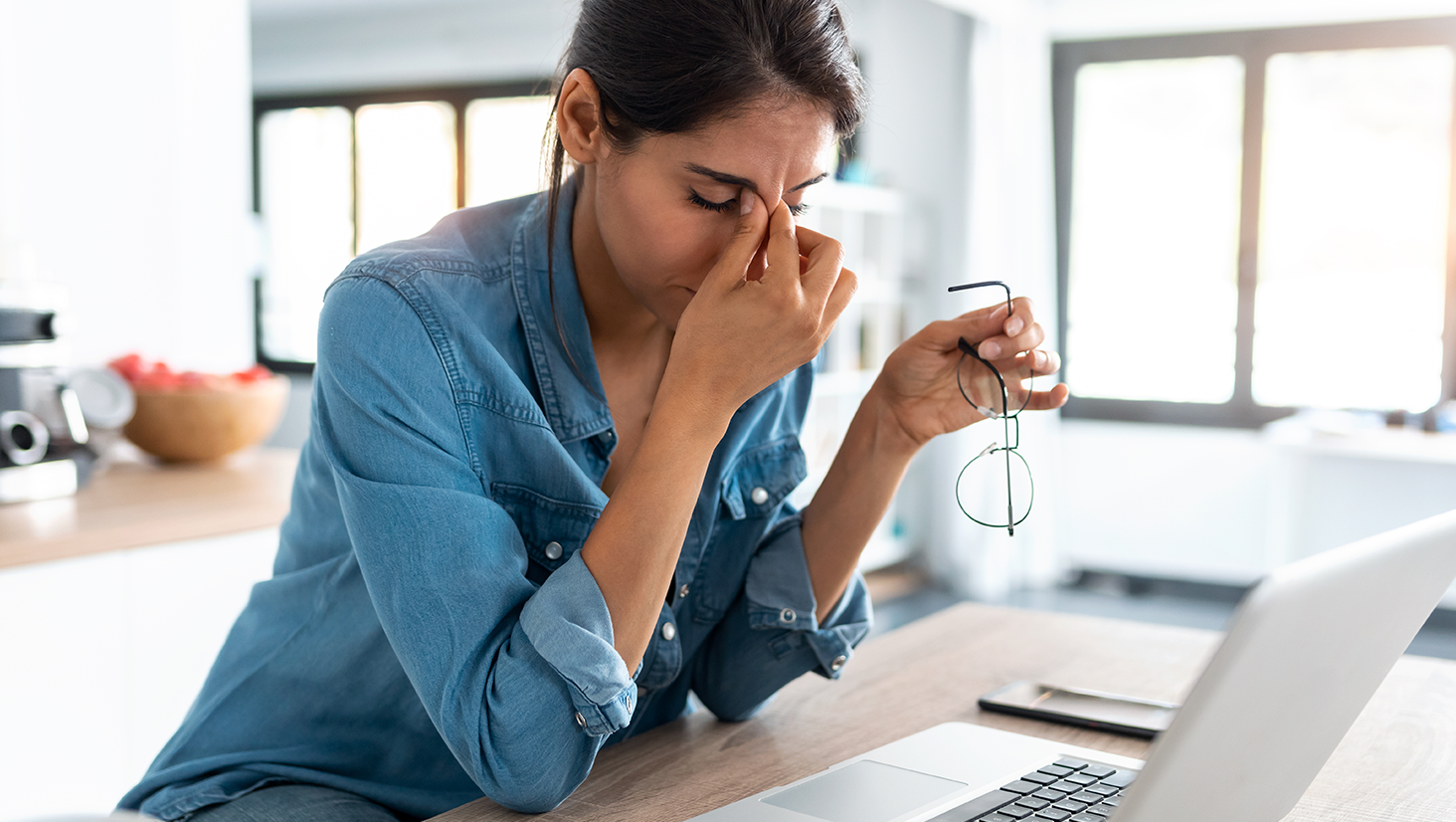 Shot of stressed business woman working from home on laptop looking worried, tired and overwhelmed.